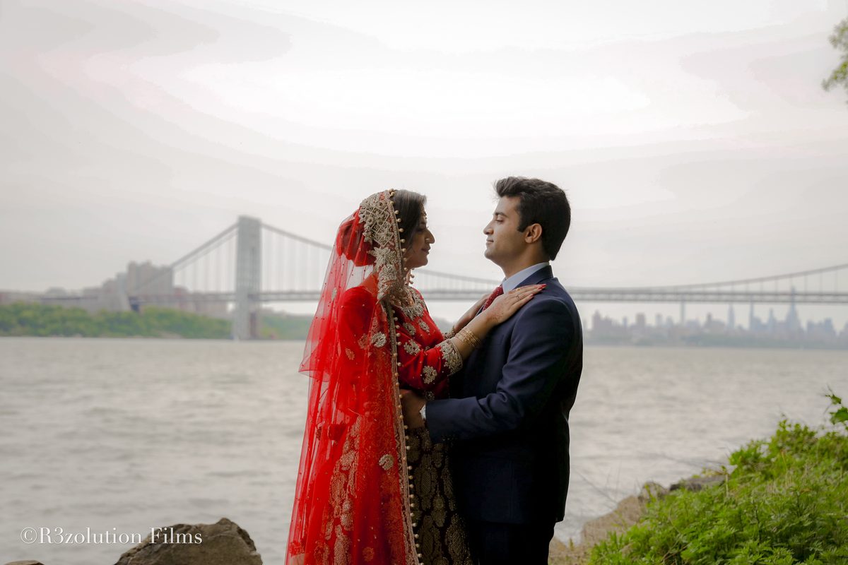A bride in a red veil with her groom at the waterfront, shot by RF Studios